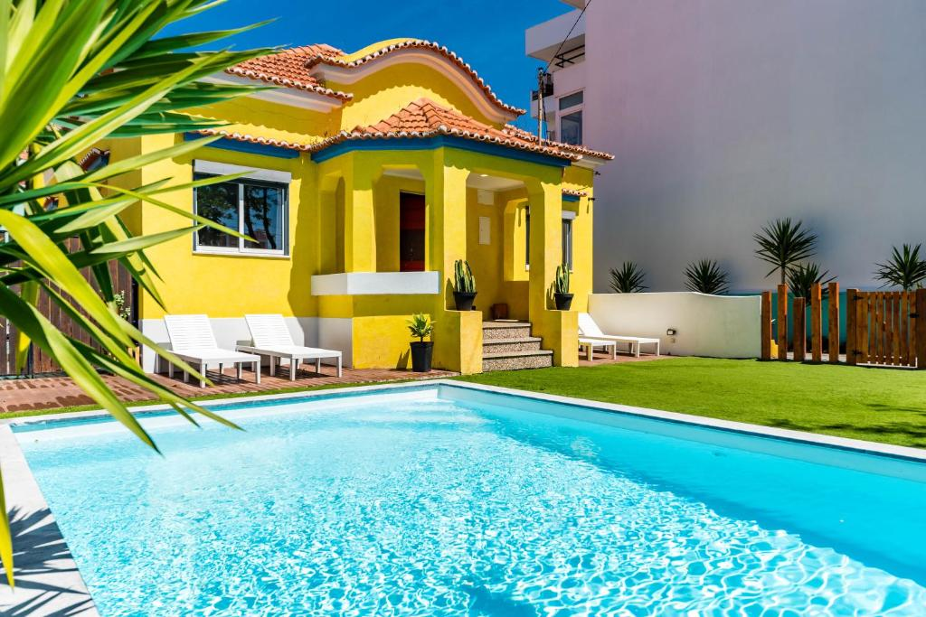 Image of a yellow house with a pool infront of it!